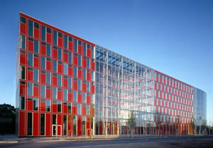 Referenz der Pandomus GmbH im Bereich Medienbranche, Facility Management und technische Gebäudeausrüstung, rotes, schmales Gebäude aus Glas, rotes Glas, das fast schon durchsichtig wirkt